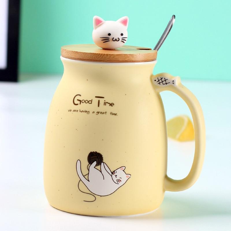 A colorful ceramic coffee mug featuring an adorable cat cartoon design, available in pink, yellow, and blue.