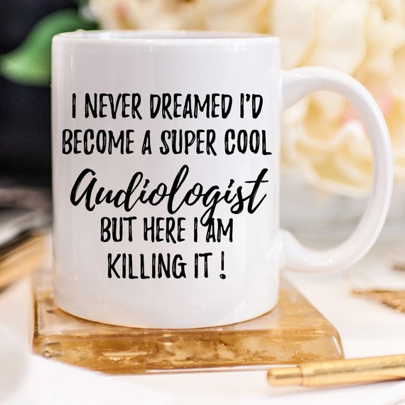 A white ceramic Audiologist Mug featuring a vibrant design on both sides, perfect for coffee or tea.