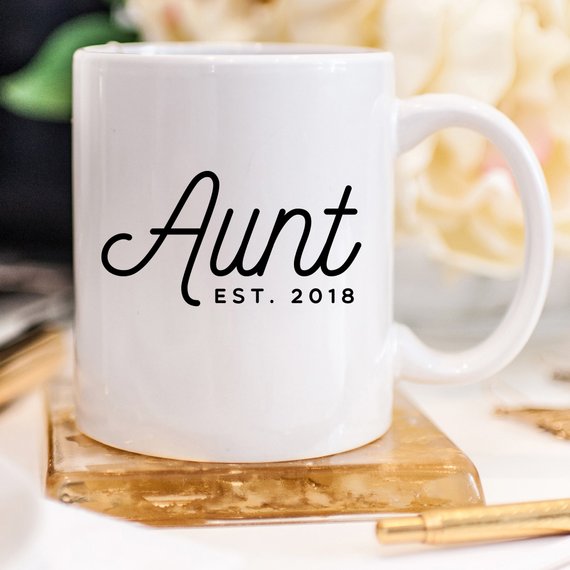 A white ceramic mug with 'Aunt Est 2018' printed on both sides, showcasing a vibrant design.