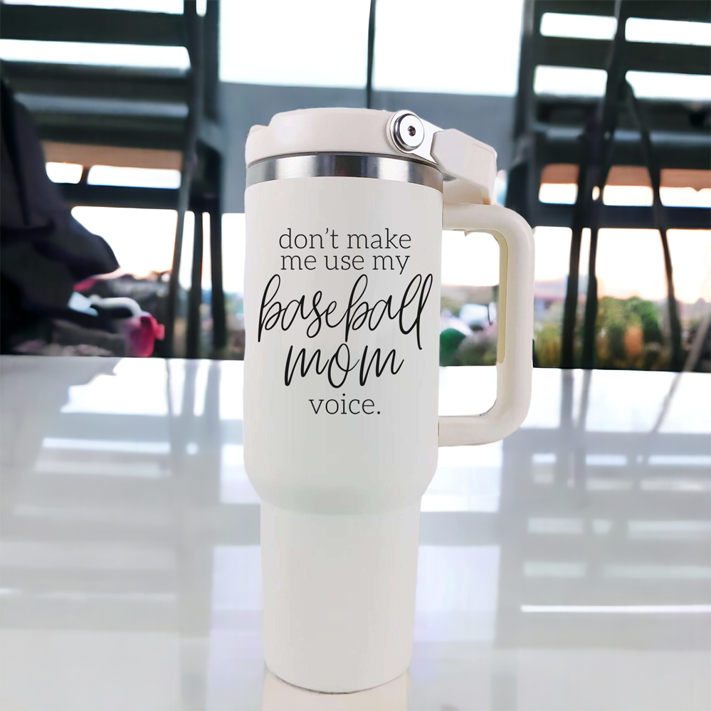 A stylish cream tumbler with a stainless steel interior, featuring the phrase 'Don't Make Me Use My Baseball Mom Voice' in bold black graphic.