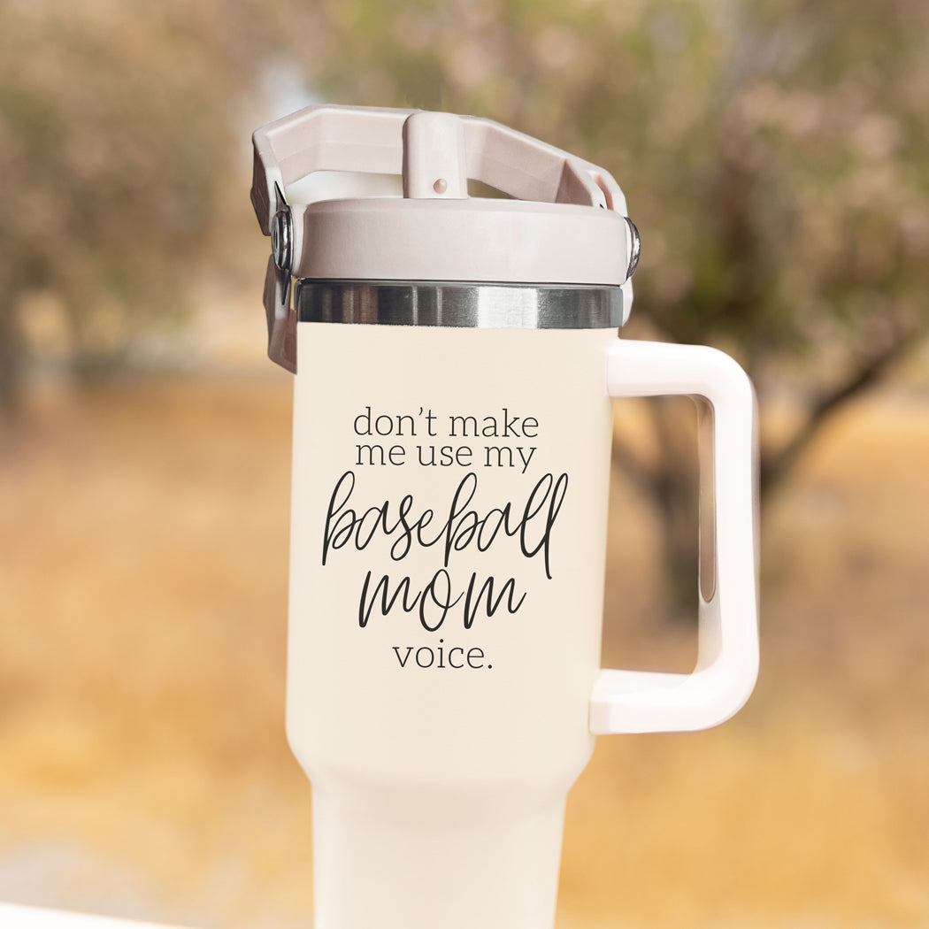 A stylish cream tumbler with a stainless steel interior, featuring the phrase 'Don't Make Me Use My Baseball Mom Voice' in bold black graphic.