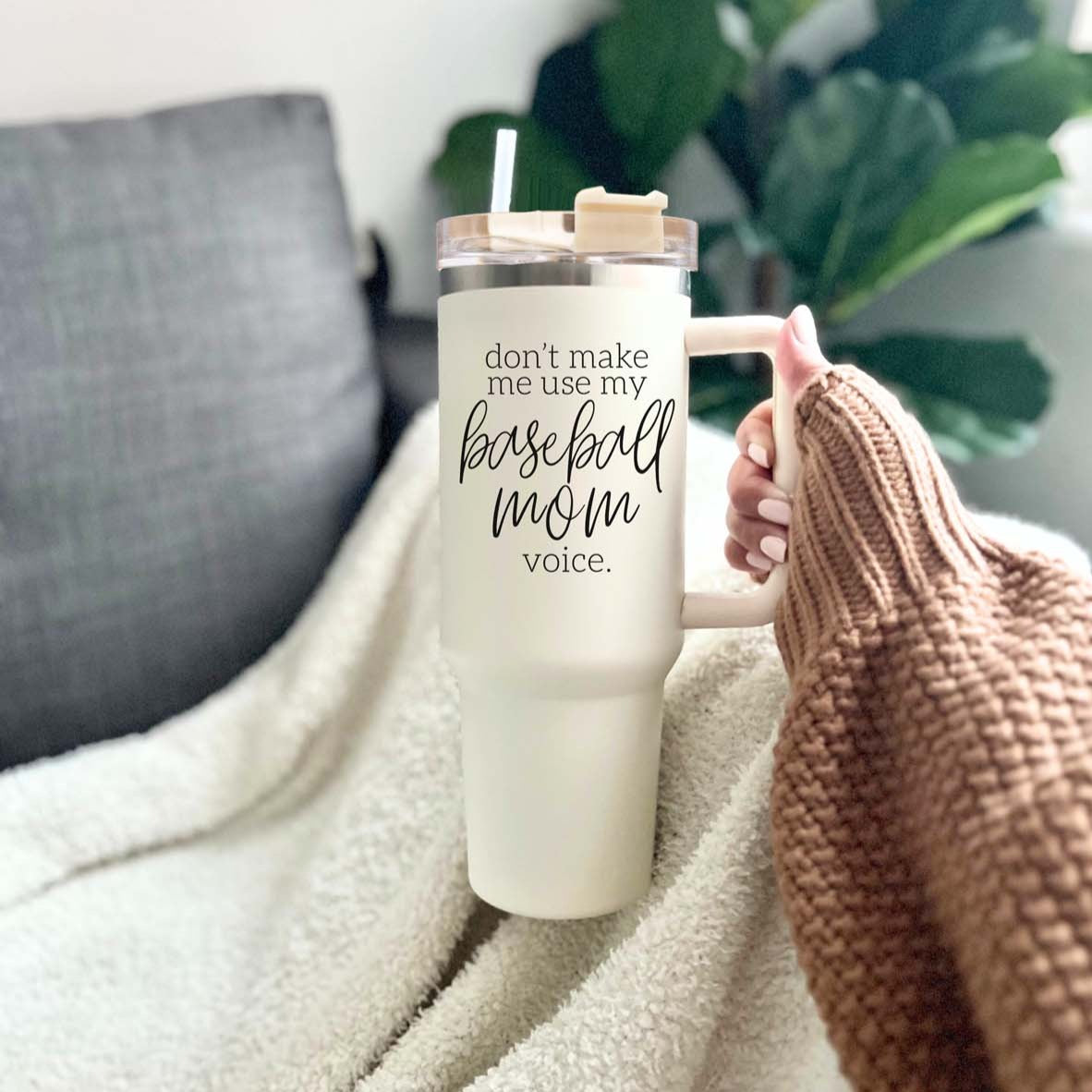 A stylish cream tumbler with a stainless steel interior, featuring the phrase 'Don't Make Me Use My Baseball Mom Voice' in bold black graphic.