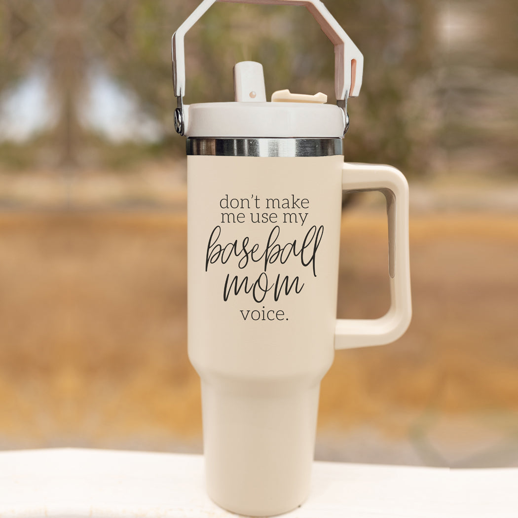 A stylish cream tumbler with a stainless steel interior, featuring the phrase 'Don't Make Me Use My Baseball Mom Voice' in bold black graphic.