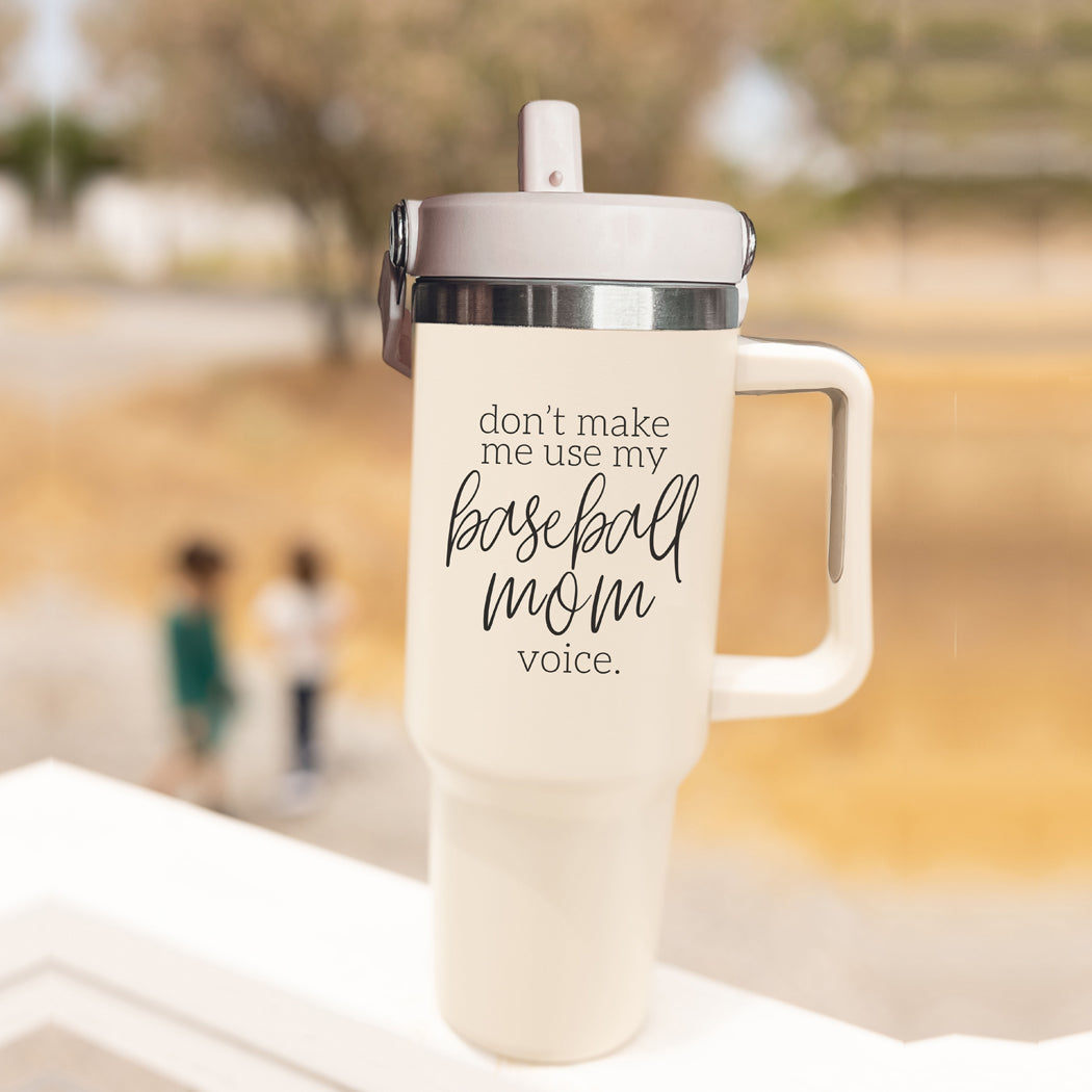 A stylish cream tumbler with a stainless steel interior, featuring the phrase 'Don't Make Me Use My Baseball Mom Voice' in bold black graphic.