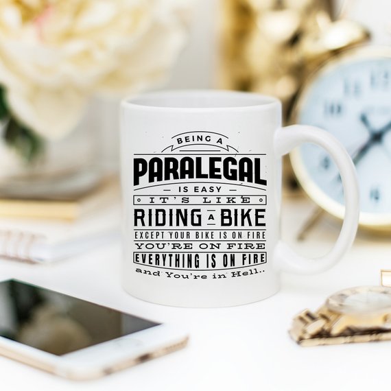 A humorous coffee mug featuring the phrase 'Being A Paralegal Is Easy' with a fiery design, perfect for paralegals.