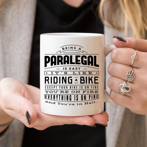 A humorous coffee mug featuring the phrase 'Being A Paralegal Is Easy' with a fiery design, perfect for paralegals.