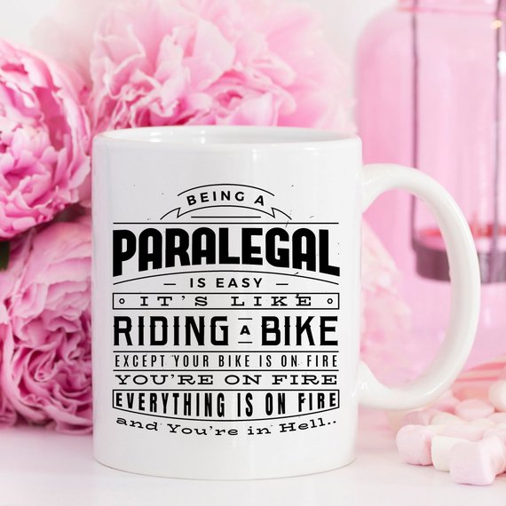 A humorous coffee mug featuring the phrase 'Being A Paralegal Is Easy' with a fiery design, perfect for paralegals.