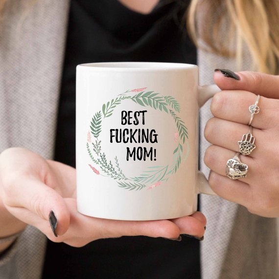 A white ceramic mug with 'Best Fucking Mom' printed on both sides, showcasing a vibrant design.