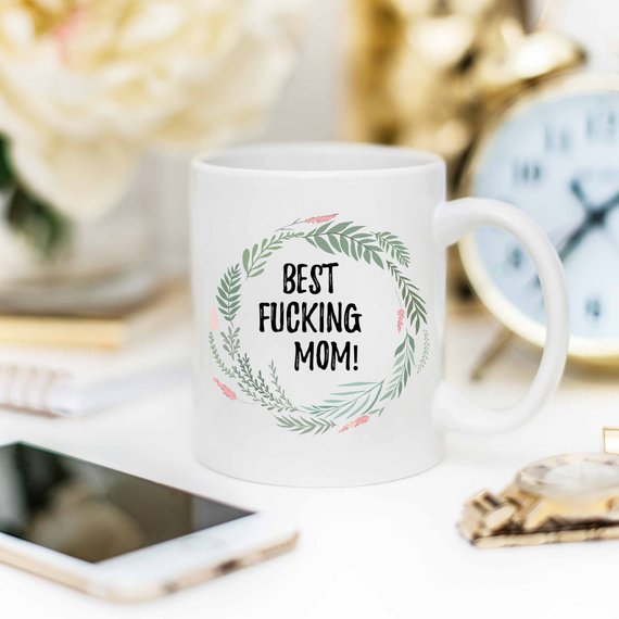 A white ceramic mug with 'Best Fucking Mom' printed on both sides, showcasing a vibrant design.