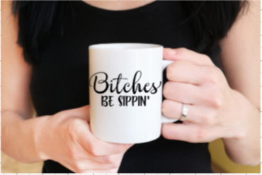 A white ceramic mug with the phrase 'Bitches Be Sippin'' printed on it, featuring rounded corners and a C-handle.