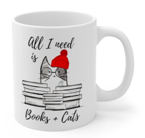 A white ceramic mug with the phrase 'All I Need is Books & Cats' printed on it, perfect for book lovers.