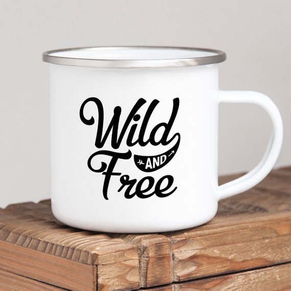 White enamel camping mug with stainless steel rim featuring 'Wild and Free' design on both sides, perfect for outdoor adventures.