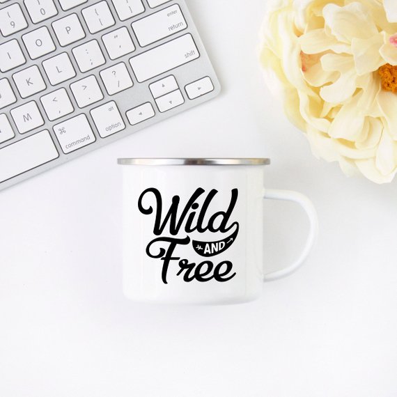 White enamel camping mug with stainless steel rim featuring 'Wild and Free' design on both sides, perfect for outdoor adventures.