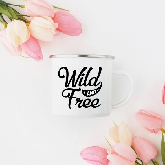 White enamel camping mug with stainless steel rim featuring 'Wild and Free' design on both sides, perfect for outdoor adventures.