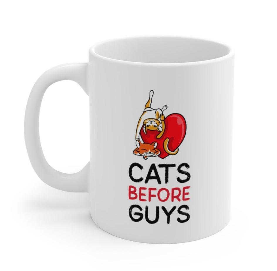 A white ceramic mug with the phrase 'Cats Before Guys' printed on it, featuring a classic design and C-handle.