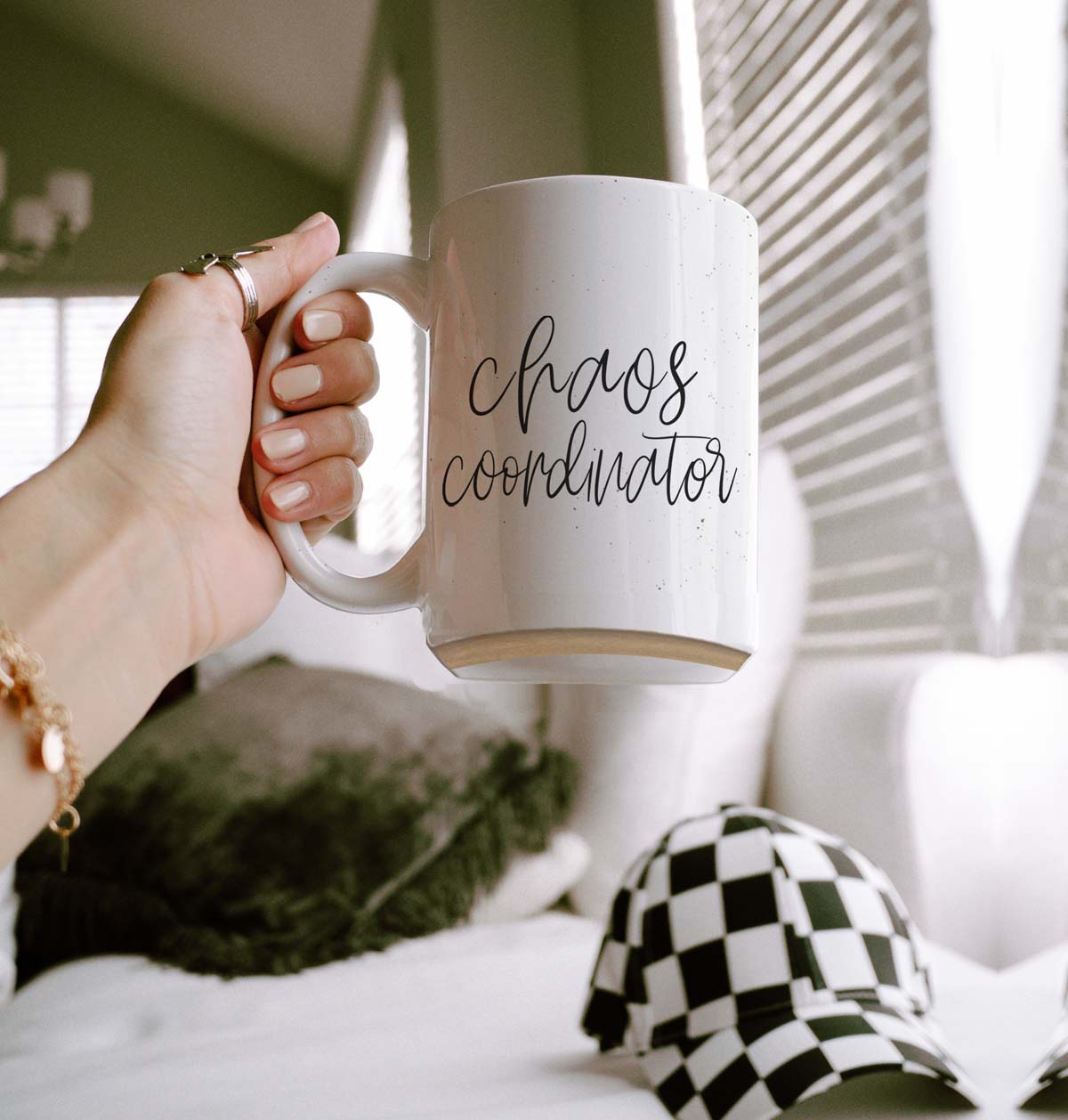 A humorous 'Chaos Coordinator' 16oz coffee mug featuring a black graphic on an off-white ceramic body with dark speckles.