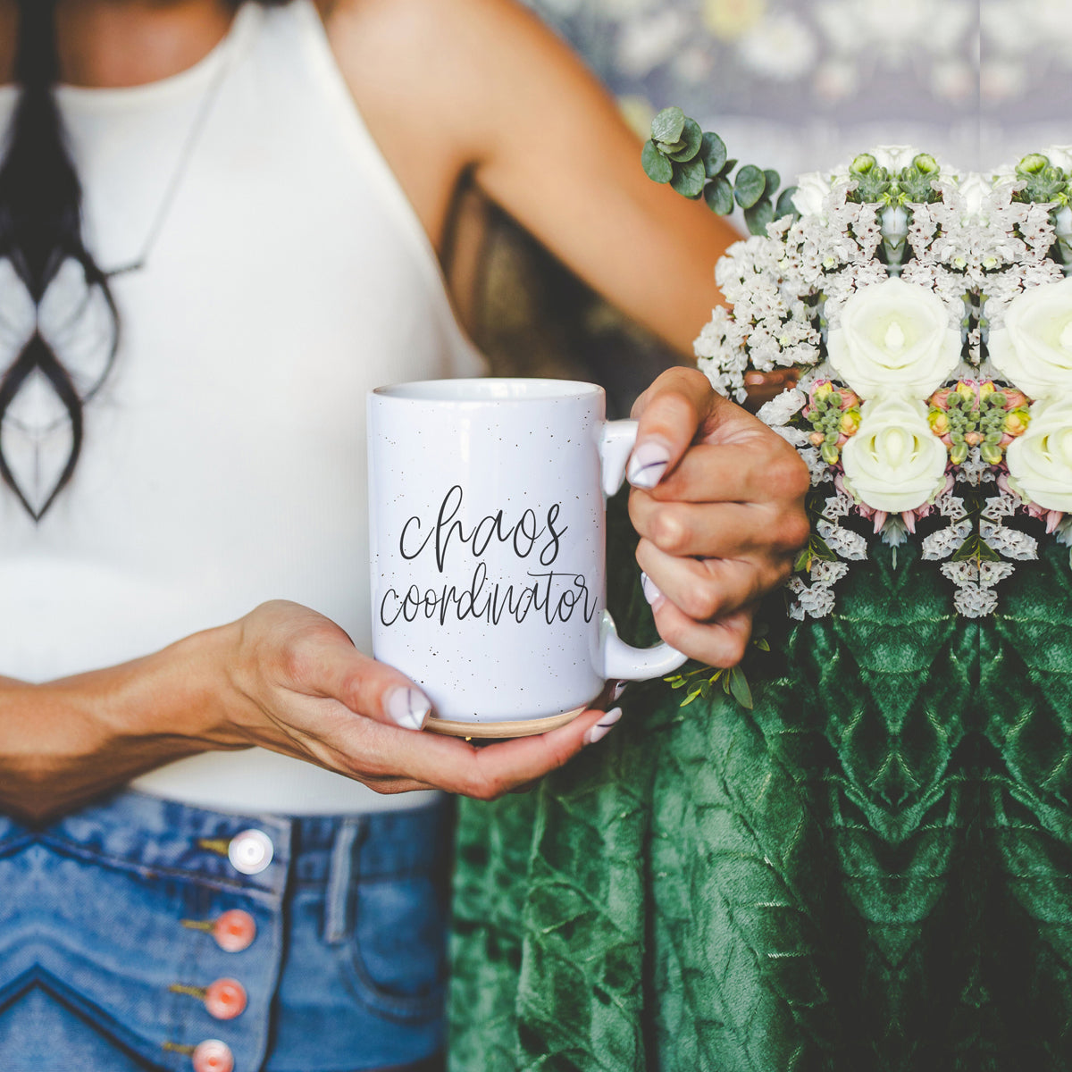 A humorous 'Chaos Coordinator' 16oz coffee mug featuring a black graphic on an off-white ceramic body with dark speckles.