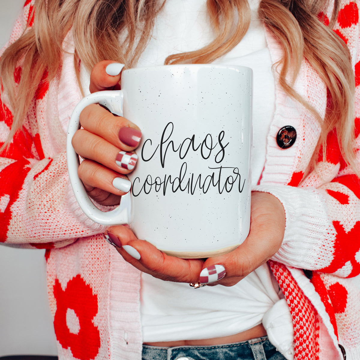 A humorous 'Chaos Coordinator' 16oz coffee mug featuring a black graphic on an off-white ceramic body with dark speckles.