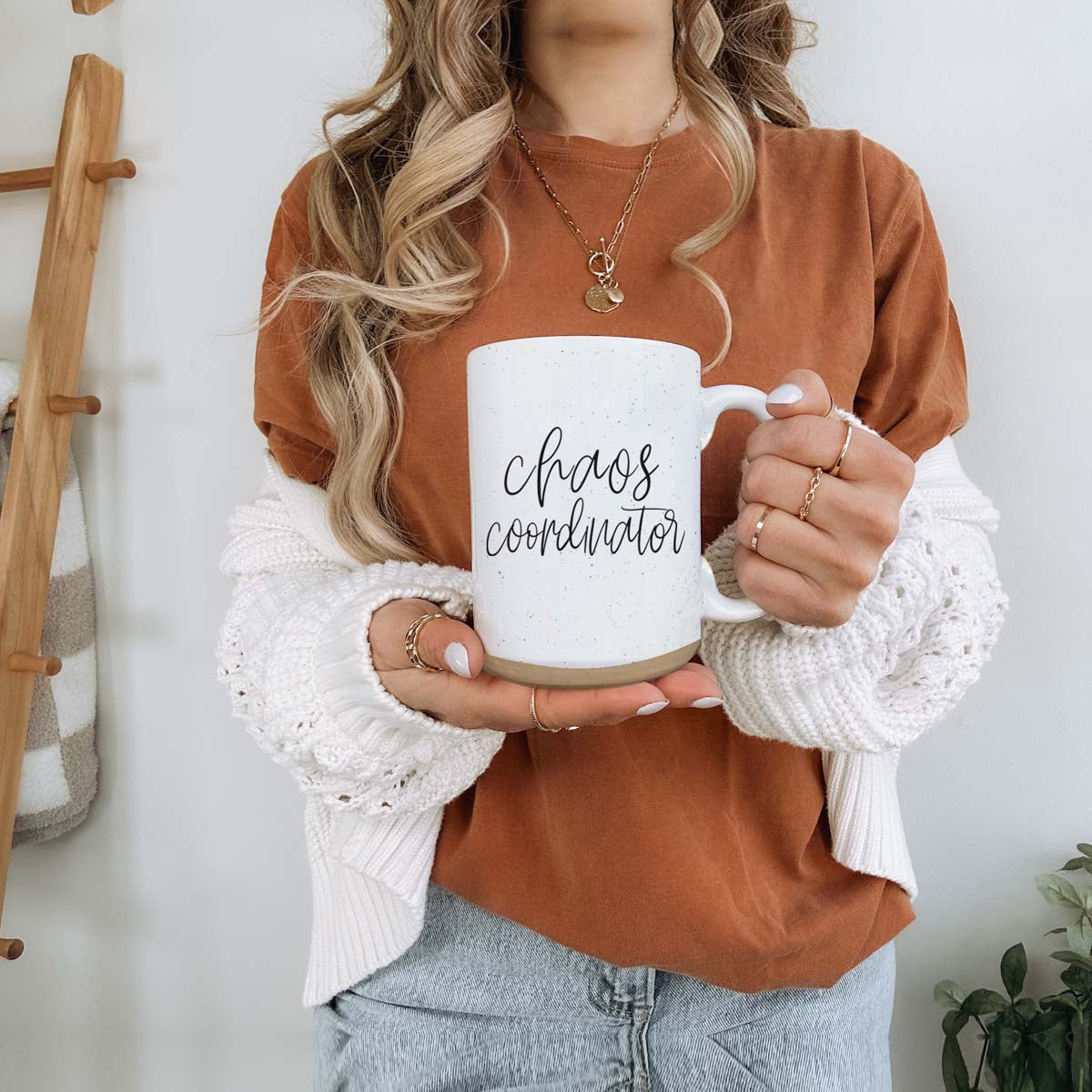 A humorous 'Chaos Coordinator' 16oz coffee mug featuring a black graphic on an off-white ceramic body with dark speckles.