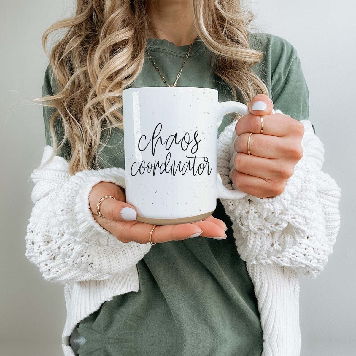 A humorous 'Chaos Coordinator' 16oz coffee mug featuring a black graphic on an off-white ceramic body with dark speckles.