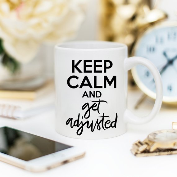 A humorous coffee mug featuring the phrase 'Keep Calm And Get Adjusted', designed for chiropractors, made of high-quality ceramic.