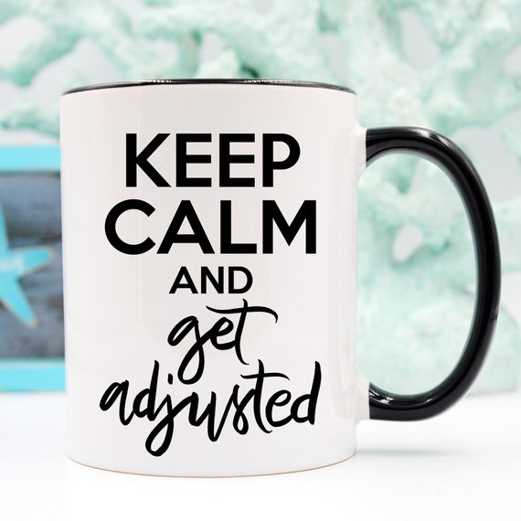 A humorous coffee mug featuring the phrase 'Keep Calm And Get Adjusted', designed for chiropractors, made of high-quality ceramic.