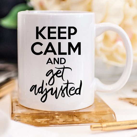 A humorous coffee mug featuring the phrase 'Keep Calm And Get Adjusted', designed for chiropractors, made of high-quality ceramic.