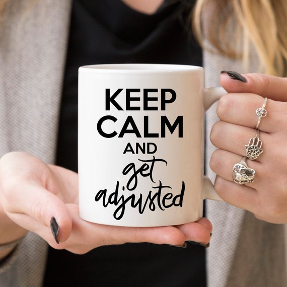 A humorous coffee mug featuring the phrase 'Keep Calm And Get Adjusted', designed for chiropractors, made of high-quality ceramic.