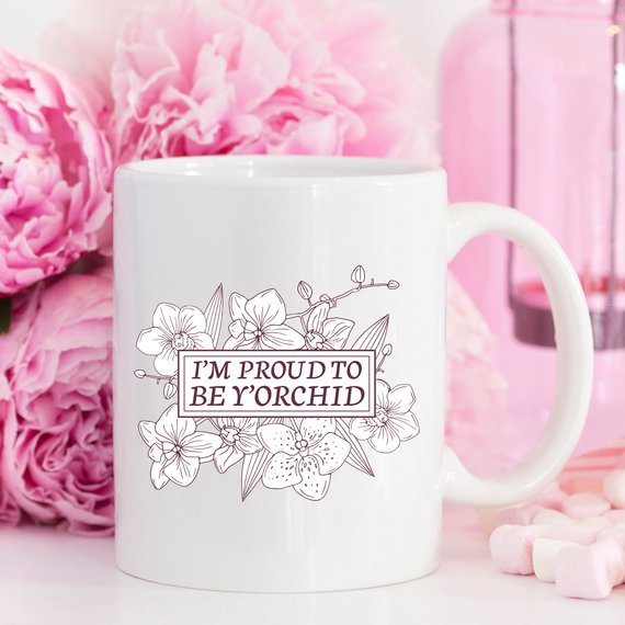 A humorous coffee mug with the phrase 'I'm Proud To Be Y'orchid', showcasing a vibrant design perfect for gifting.