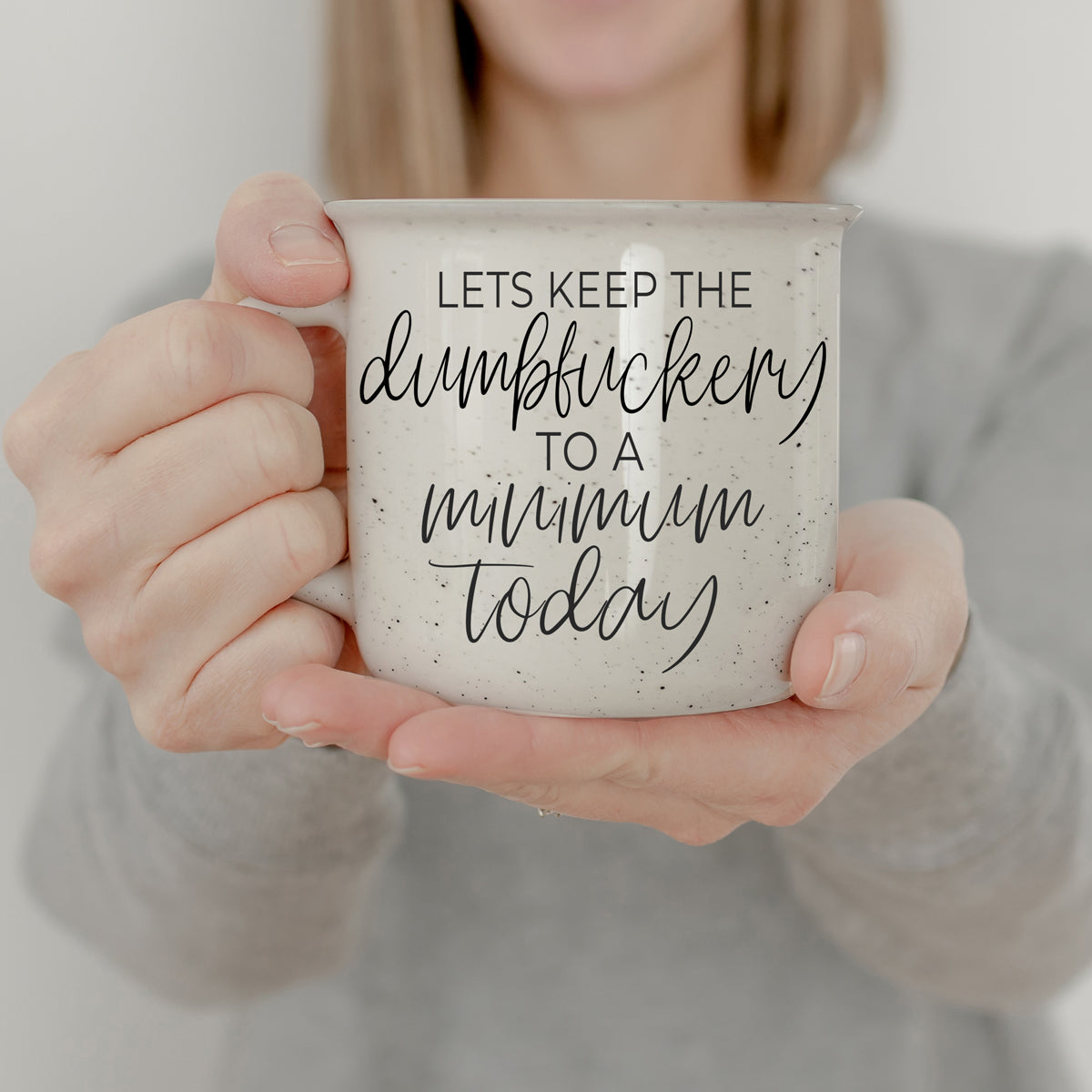 Dumbf**kery Mug featuring a humorous phrase in black lettering on a light ivory ceramic background with speckles.