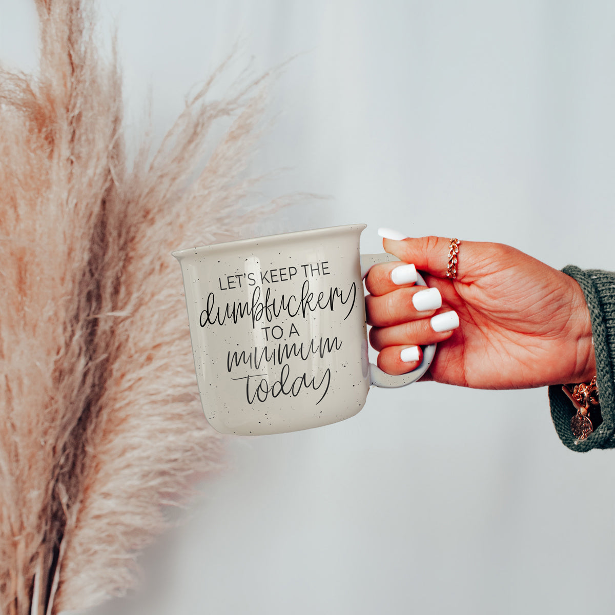 Dumbf**kery Mug featuring a humorous phrase in black lettering on a light ivory ceramic background with speckles.