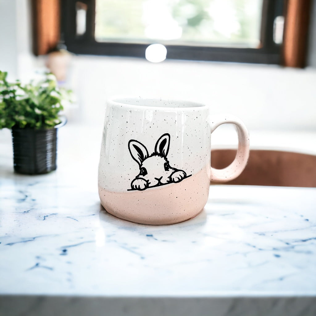 Handcrafted ceramic mug featuring a bunny silhouette and pastel pink base, perfect for coffee or tea.