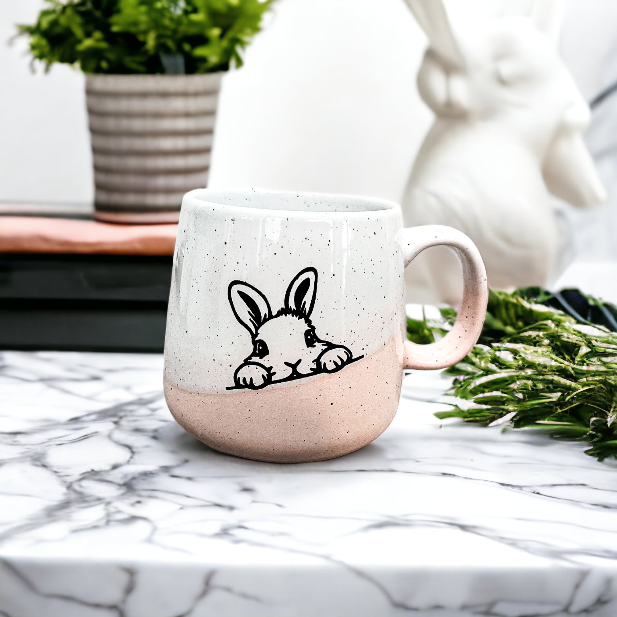 Handcrafted ceramic mug featuring a bunny silhouette and pastel pink base, perfect for coffee or tea.