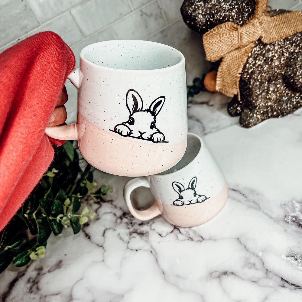 Handcrafted ceramic mug featuring a bunny silhouette and pastel pink base, perfect for coffee or tea.