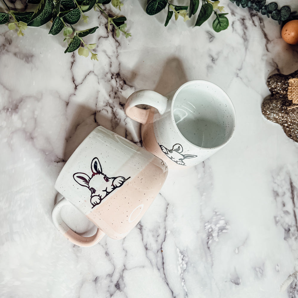 Handcrafted ceramic mug featuring a bunny silhouette and pastel pink base, perfect for coffee or tea.