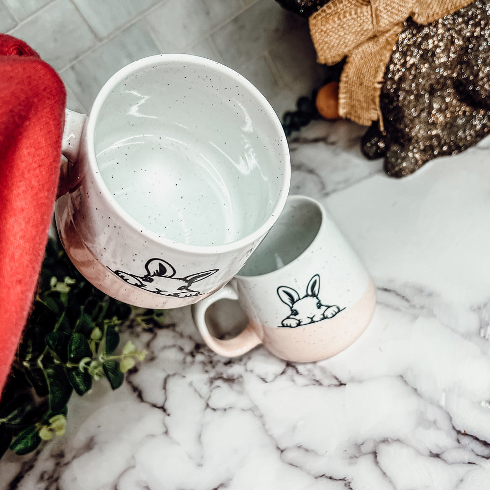 Handcrafted ceramic mug featuring a bunny silhouette and pastel pink base, perfect for coffee or tea.