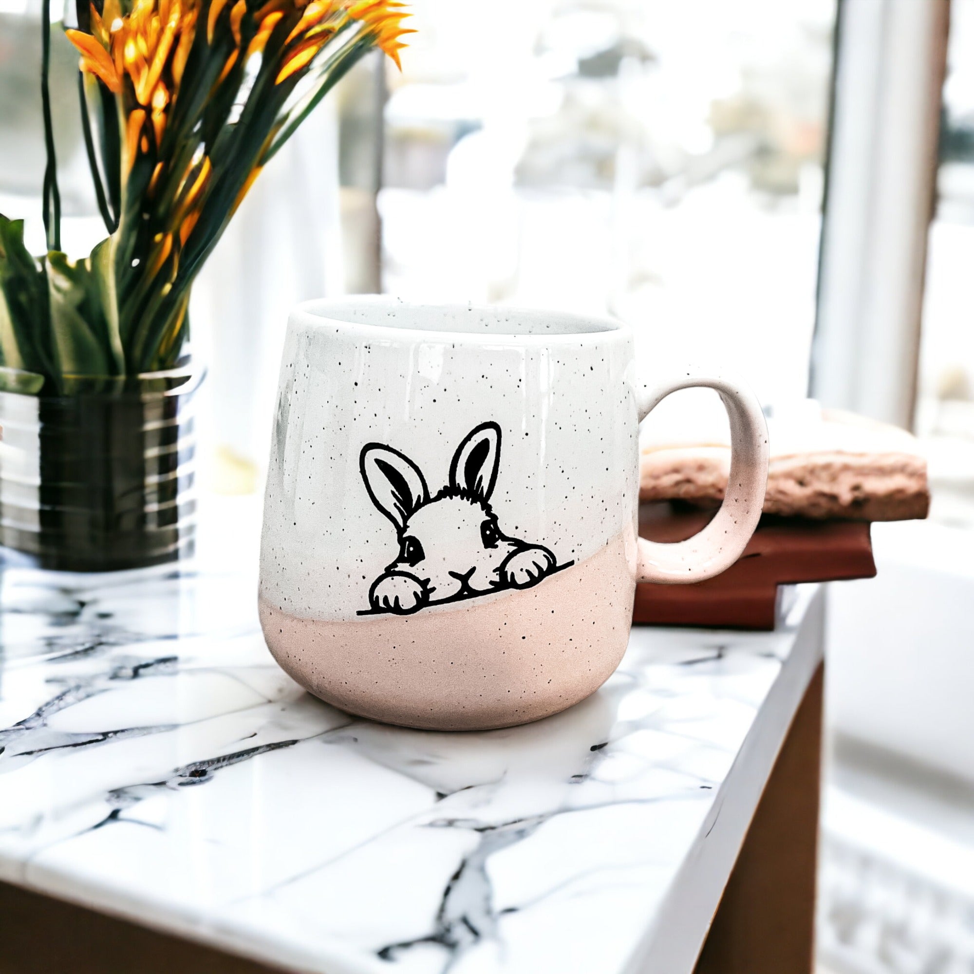 Handcrafted ceramic mug featuring a bunny silhouette and pastel pink base, perfect for coffee or tea.