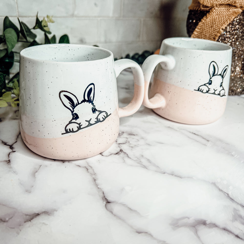 Handcrafted ceramic mug featuring a bunny silhouette and pastel pink base, perfect for coffee or tea.