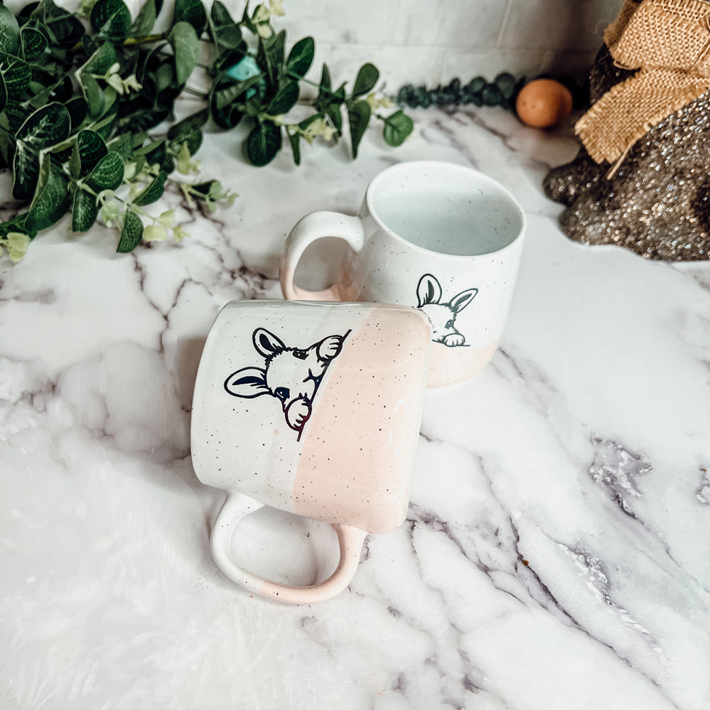 Handcrafted ceramic mug featuring a bunny silhouette and pastel pink base, perfect for coffee or tea.