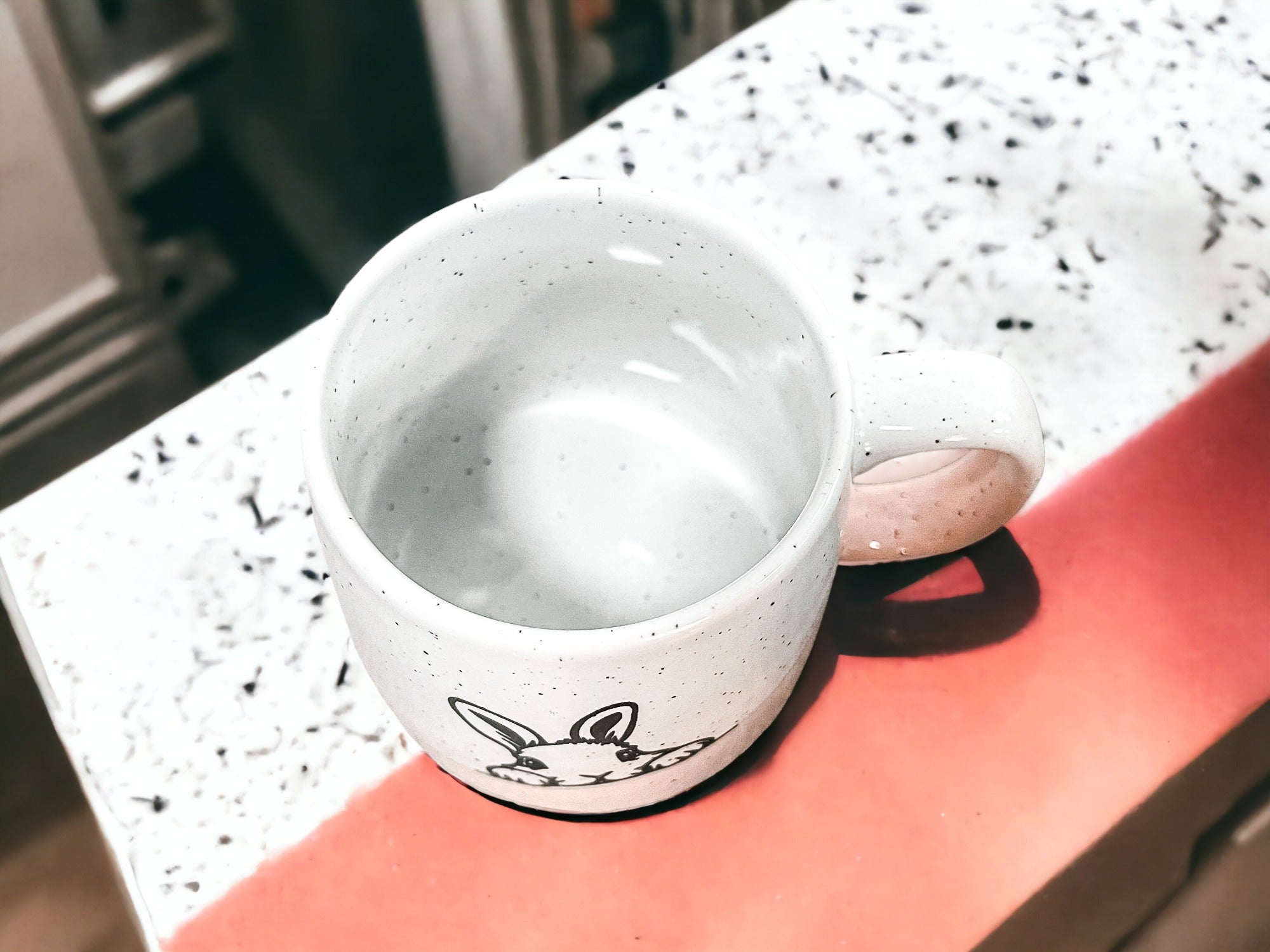 Handcrafted ceramic mug featuring a bunny silhouette and pastel pink base, perfect for coffee or tea.