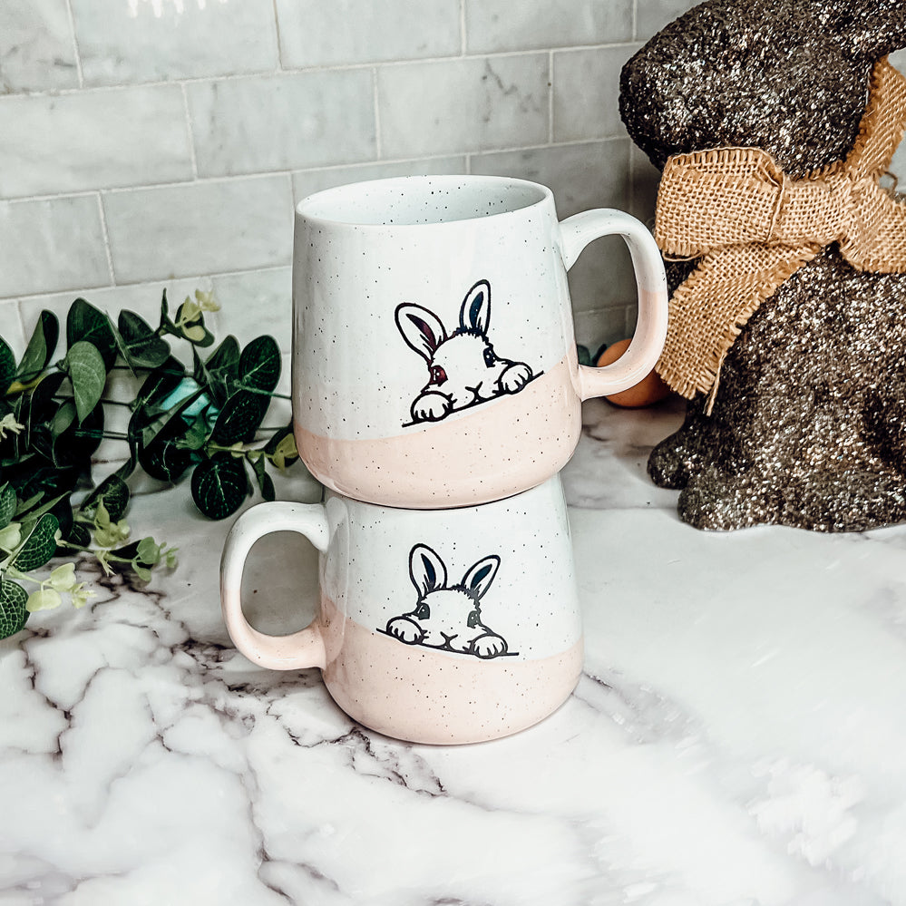 Handcrafted ceramic mug featuring a bunny silhouette and pastel pink base, perfect for coffee or tea.