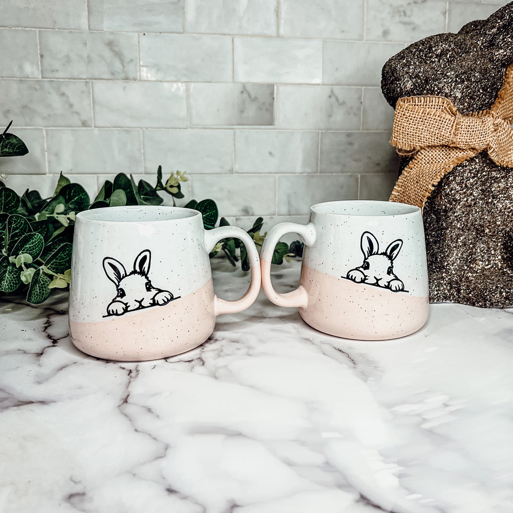 Handcrafted ceramic mug featuring a bunny silhouette and pastel pink base, perfect for coffee or tea.