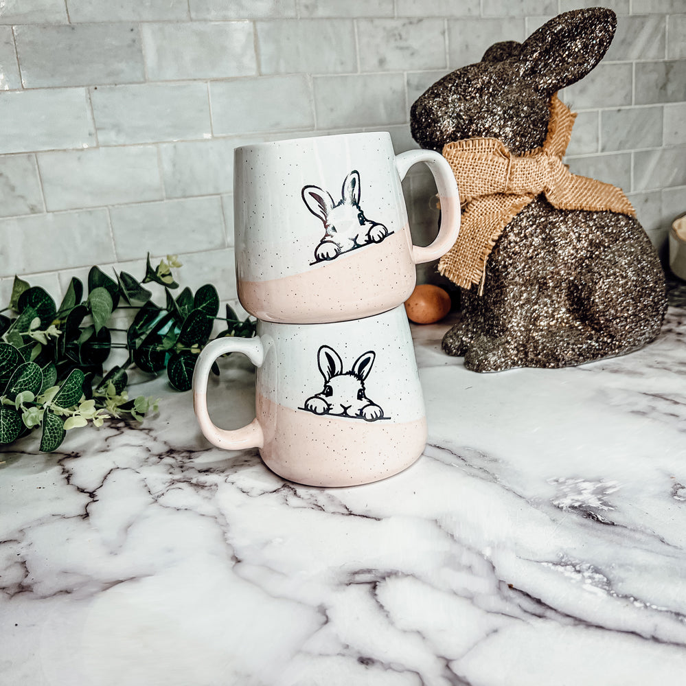 Handcrafted ceramic mug featuring a bunny silhouette and pastel pink base, perfect for coffee or tea.