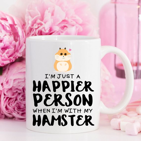 A humorous coffee mug featuring a hamster design with the text 'I'm Just A Happier Person When I'm With My Hamster', made of high-quality ceramic.