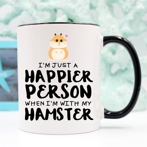 A humorous coffee mug featuring a hamster design with the text 'I'm Just A Happier Person When I'm With My Hamster', made of high-quality ceramic.