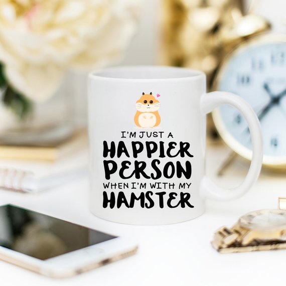 A humorous coffee mug featuring a hamster design with the text 'I'm Just A Happier Person When I'm With My Hamster', made of high-quality ceramic.