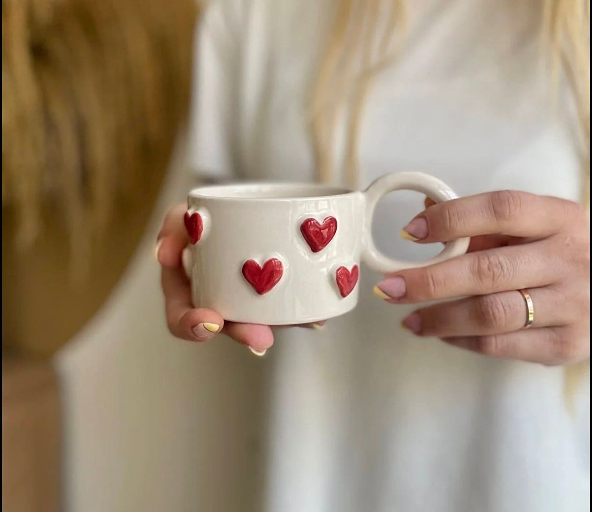 Handmade ceramic coffee mug with a small red heart design, showcasing artisan craftsmanship and vibrant colors.