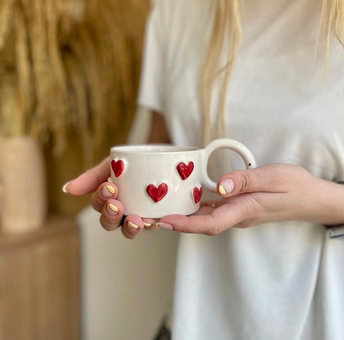 Handmade ceramic coffee mug with a small red heart design, showcasing artisan craftsmanship and vibrant colors.