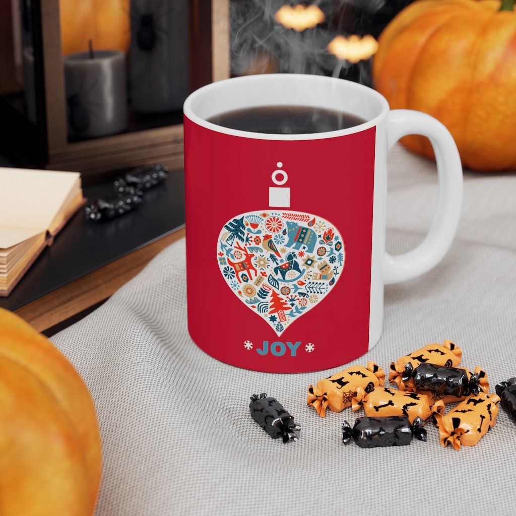 Holiday Ornament with Joy ceramic mug featuring a red backdrop and joyful design, perfect for hot beverages.