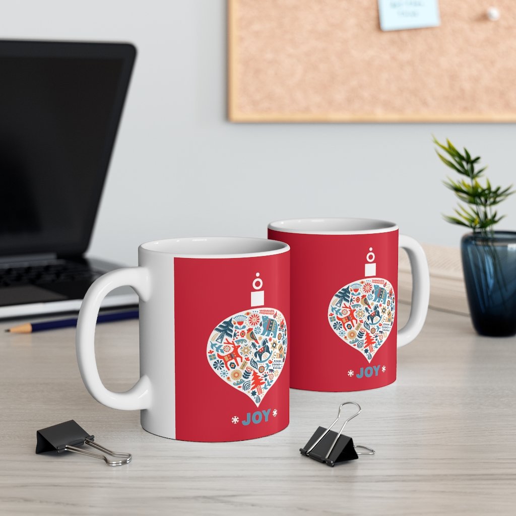 Holiday Ornament with Joy ceramic mug featuring a red backdrop and joyful design, perfect for hot beverages.